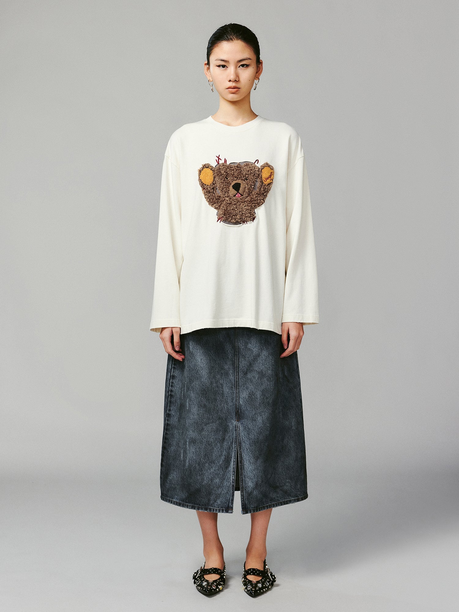 Teddy bear peeking through long-sleeve T-shirt