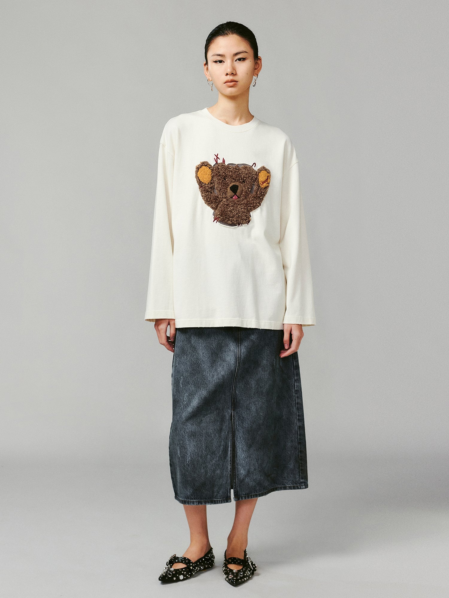 Teddy bear peeking through long-sleeve T-shirt