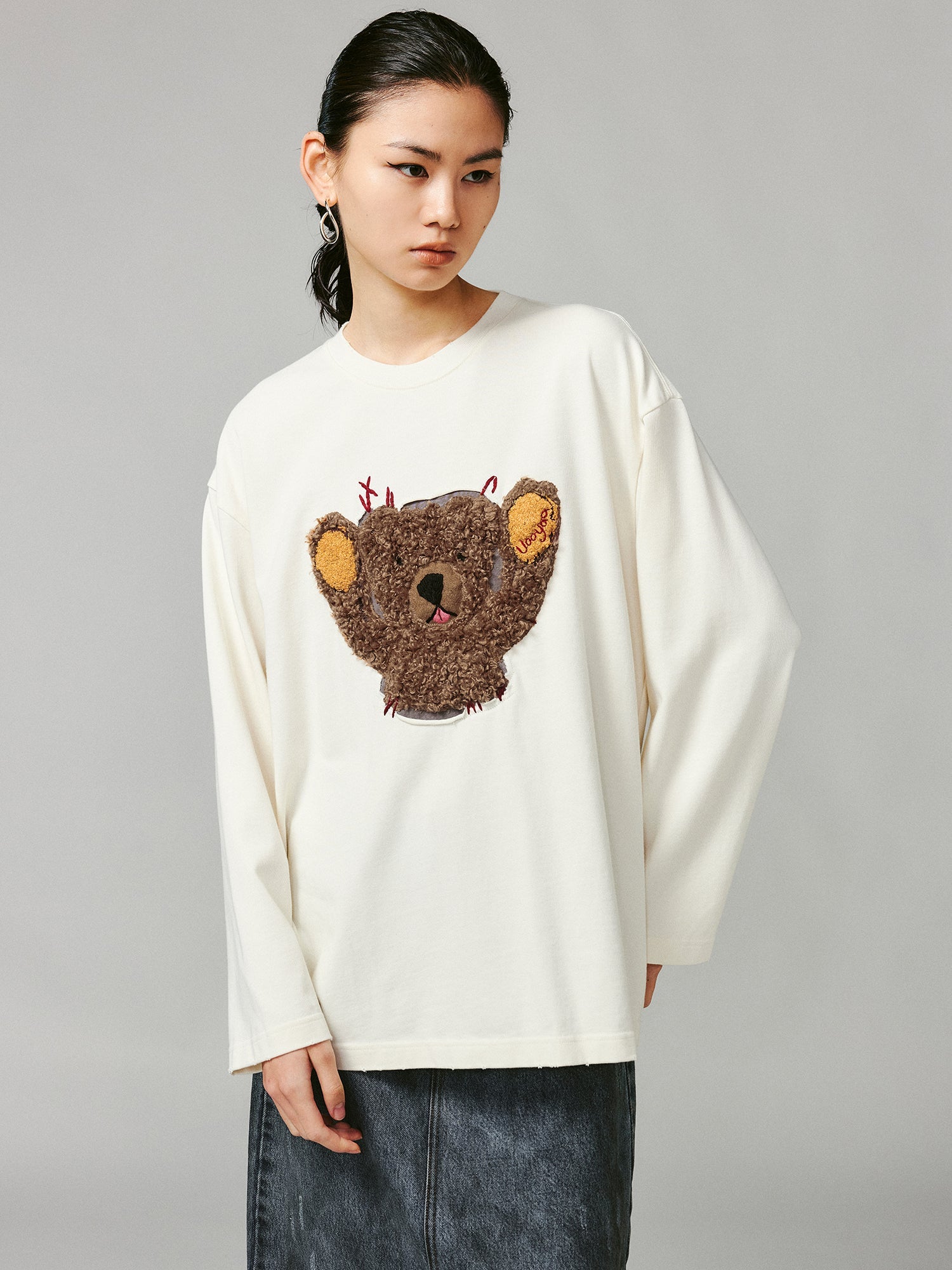 Teddy bear peeking through long-sleeve T-shirt