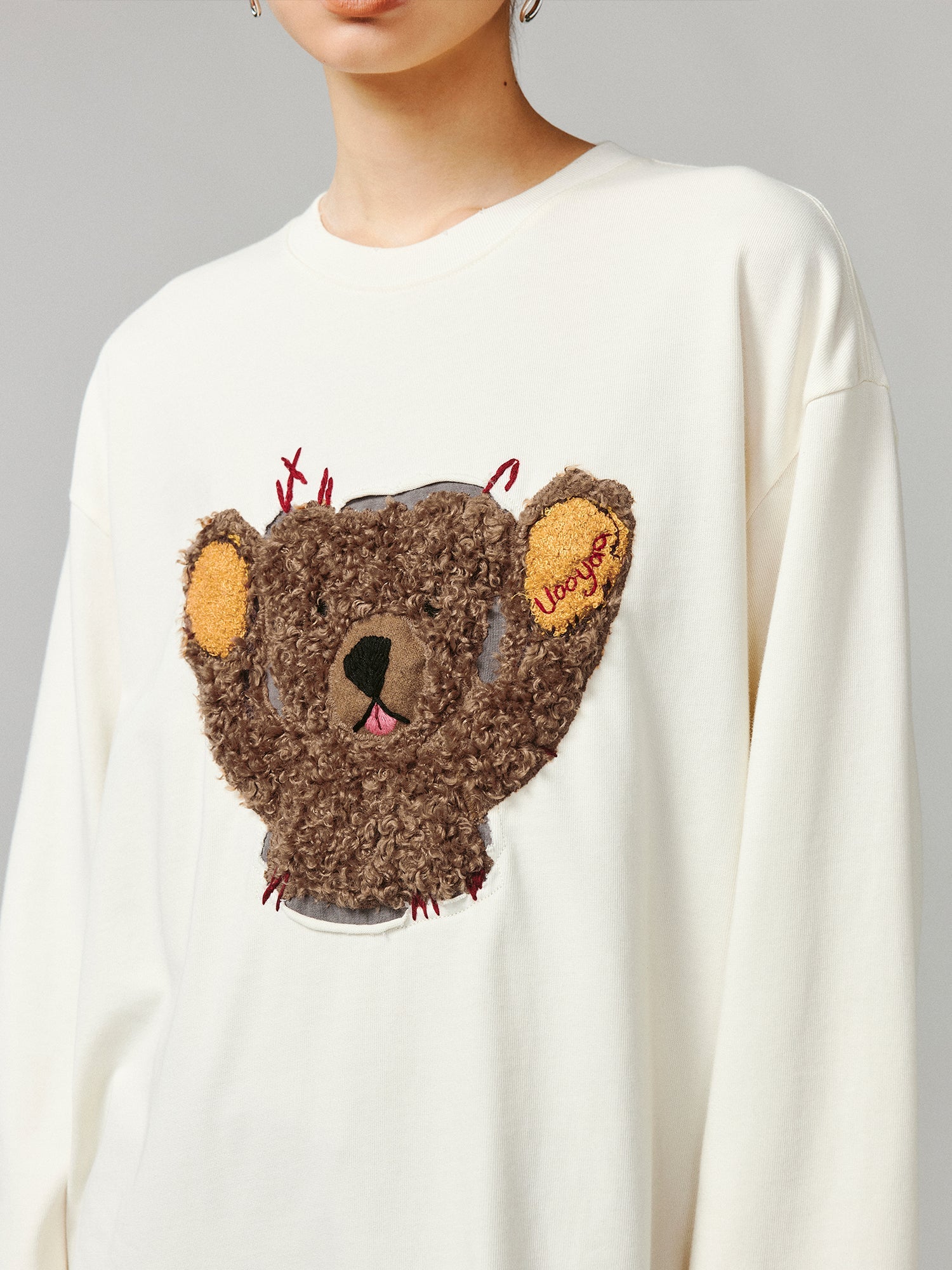 Teddy bear peeking through long-sleeve T-shirt