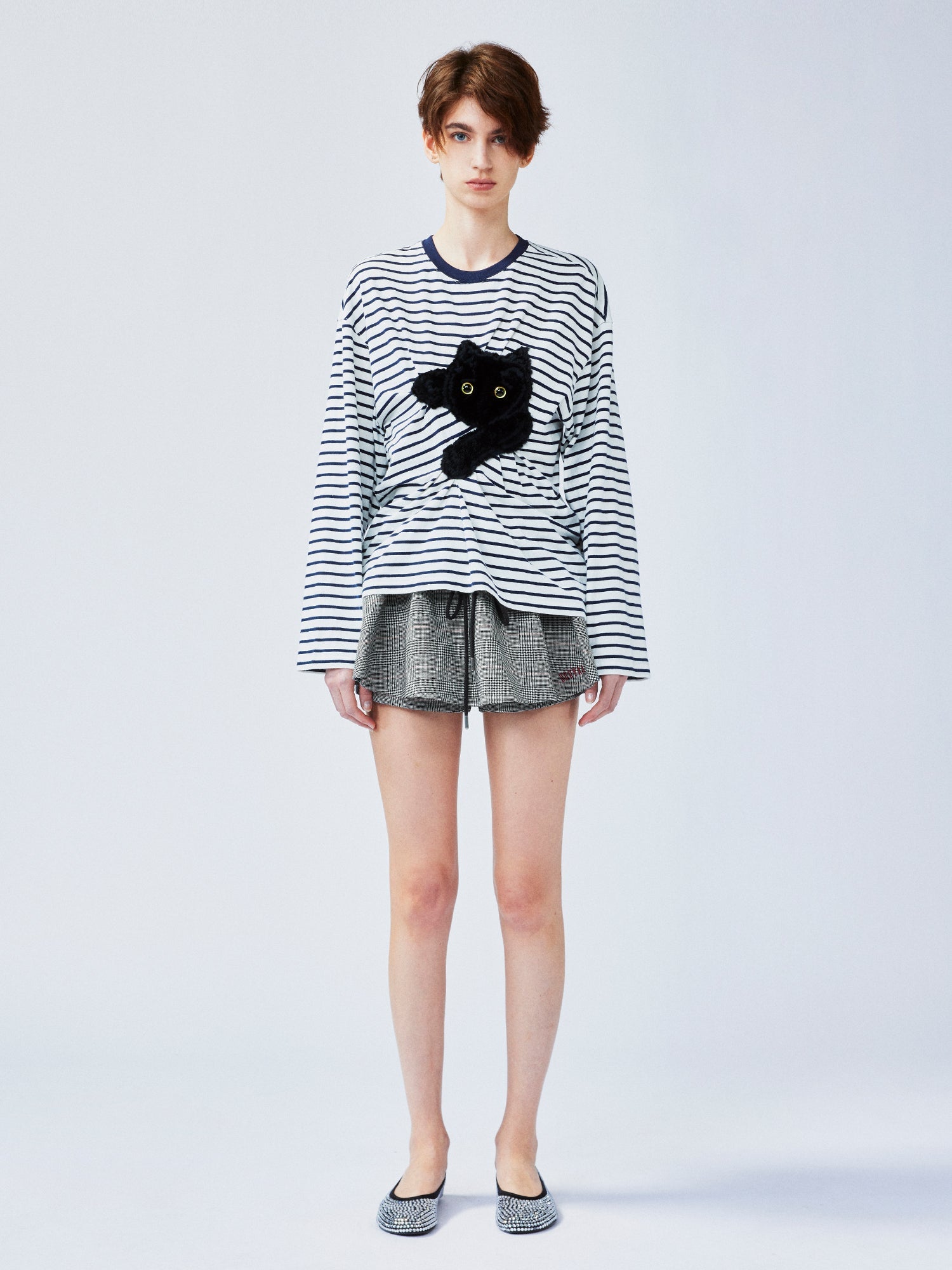 Playful cat scratching bedsheet striped T-shirt