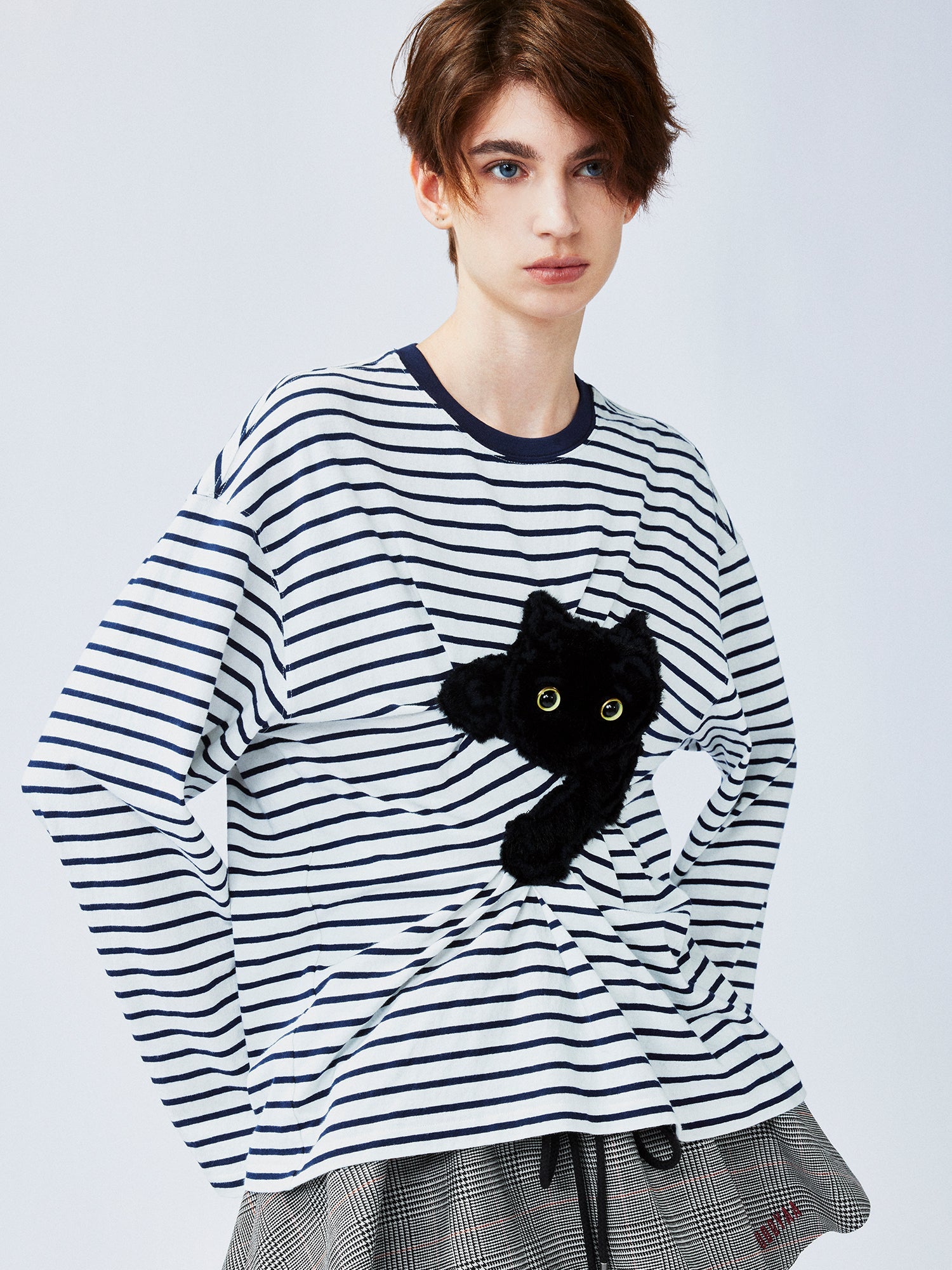 Playful cat scratching bedsheet striped T-shirt