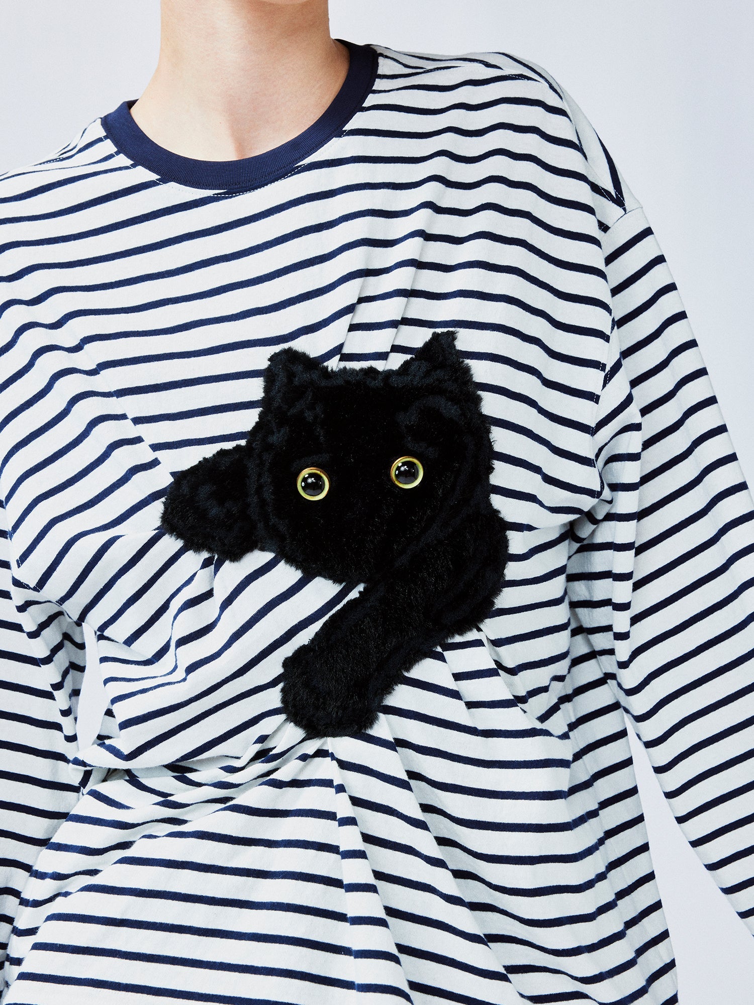 Playful cat scratching bedsheet striped T-shirt