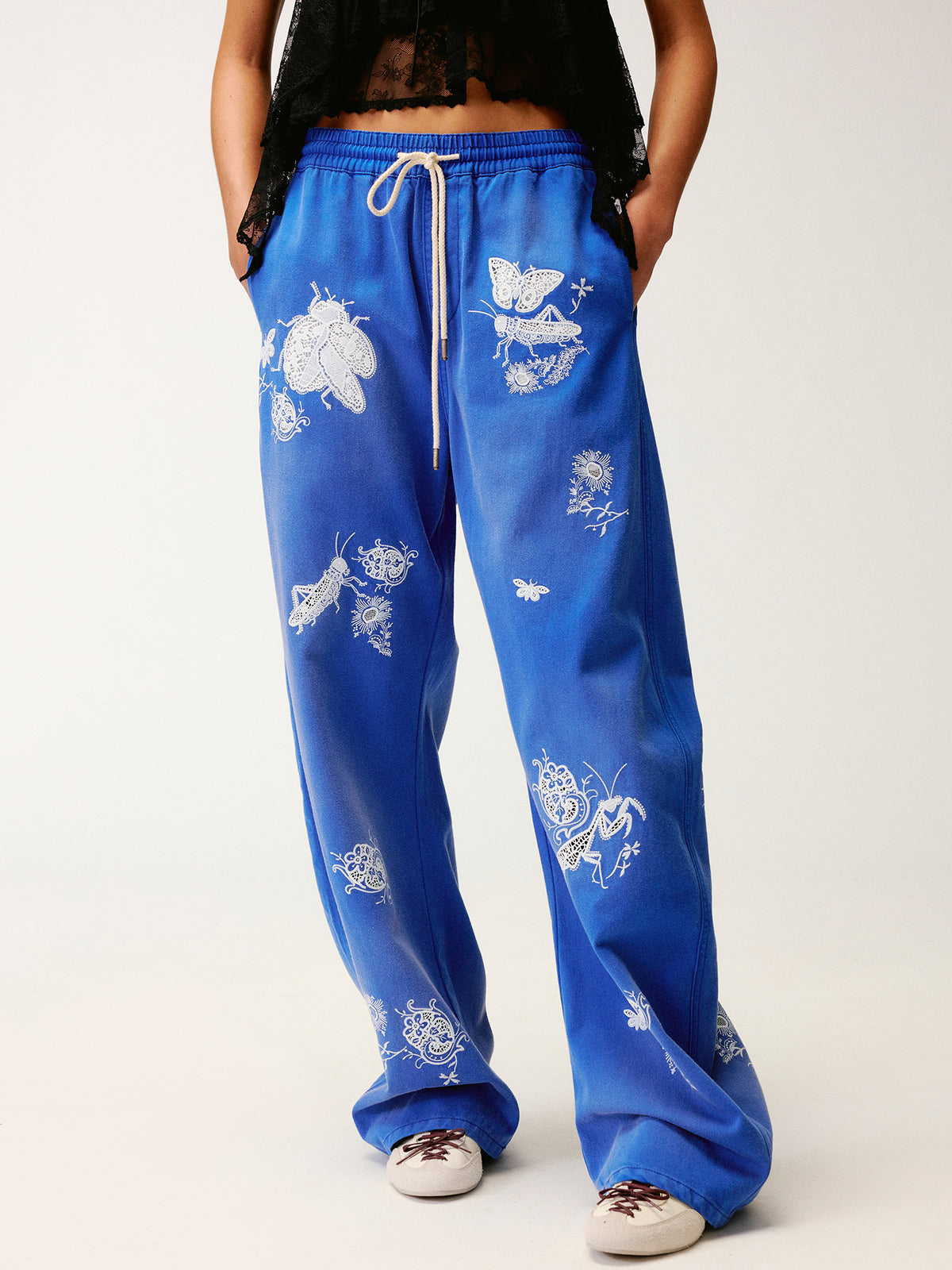 Lace insect and floral motif curved denim pants