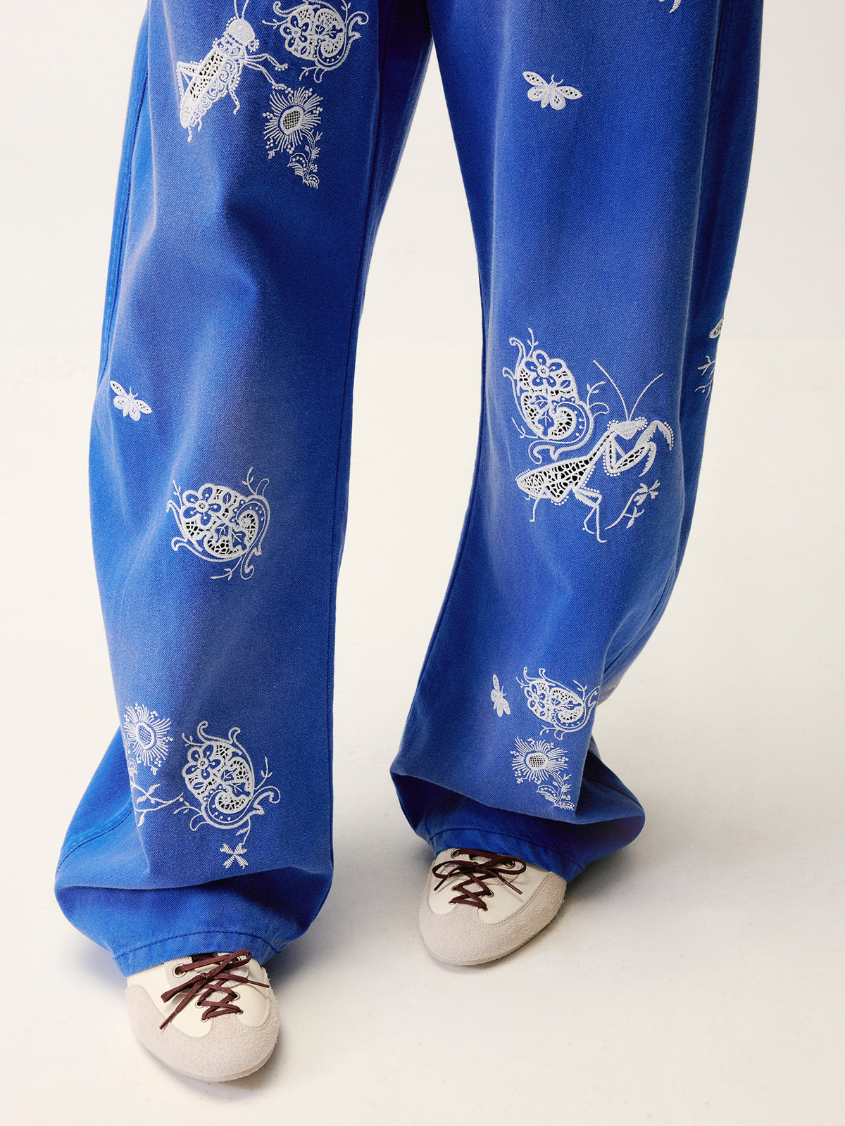 Lace insect and floral motif curved denim pants