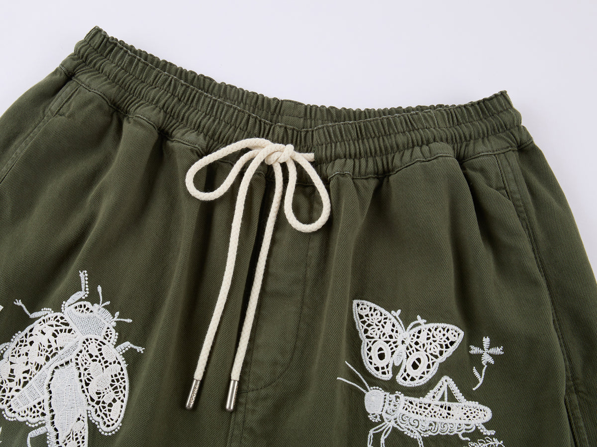 Lace insect and floral motif curved denim pants